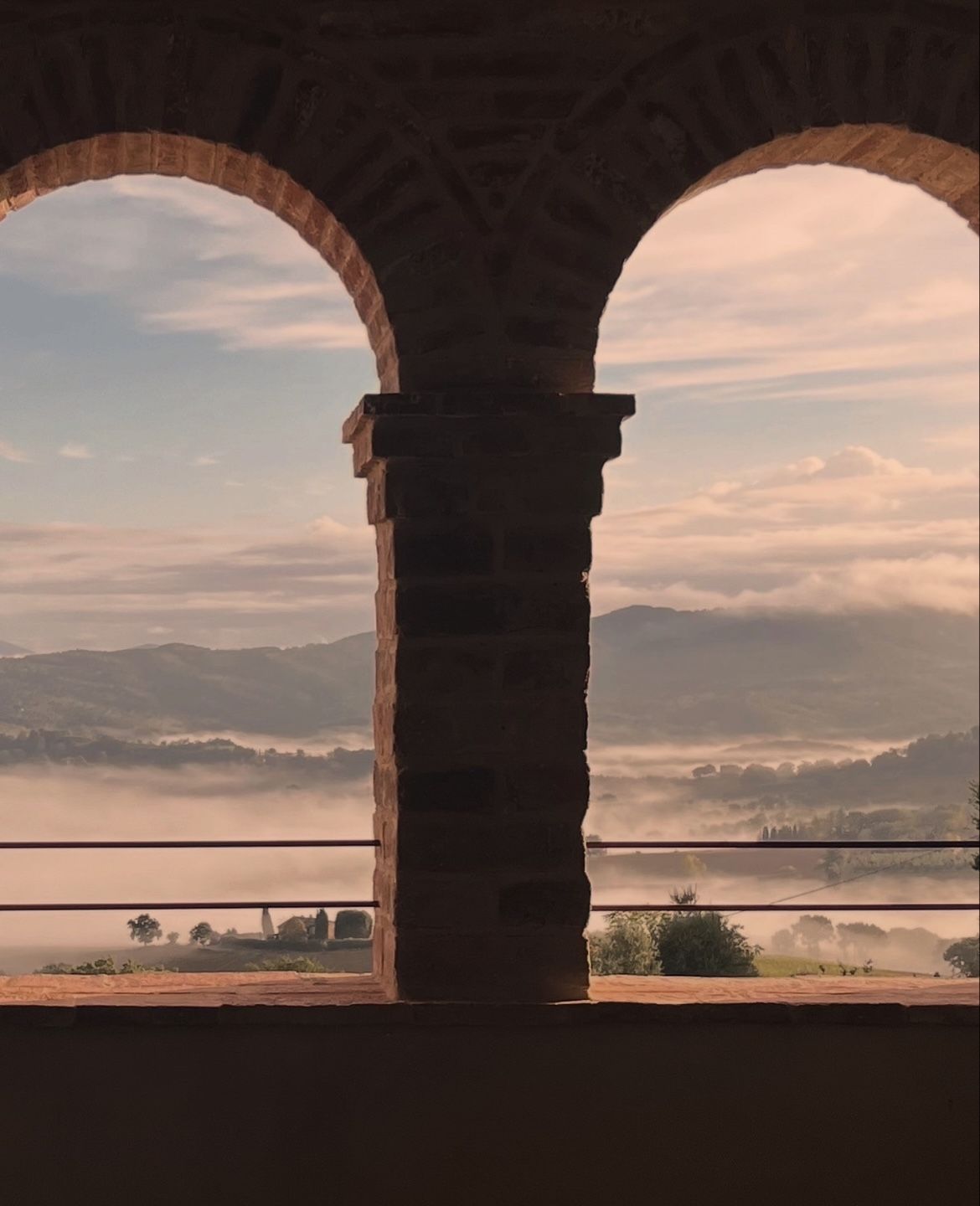Loggia ad archi in mattoni affacciata sulle colline nella nebbia del mattino