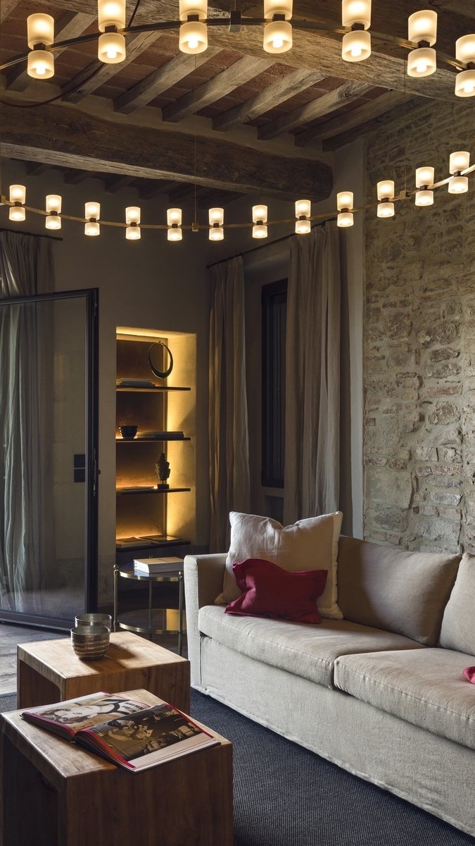 Salotto del Rastrello con soffitto a travi, pietra a vista e lampadario circolare