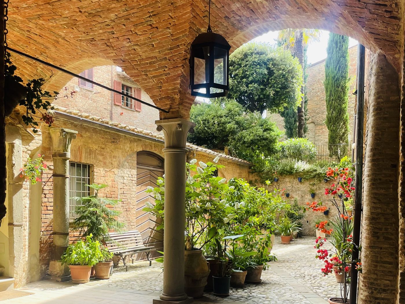 Androne di Palazzo Bandini con volta in mattoni e cortile fiorito